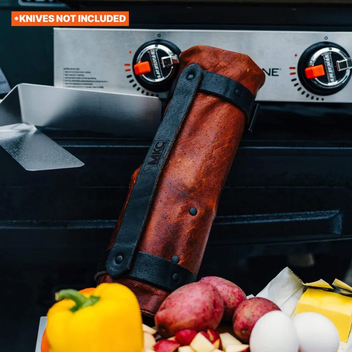 MKC Culinary Knife Roll made in the USA, featuring a rugged leather design, placed next to fresh vegetables on a grill.