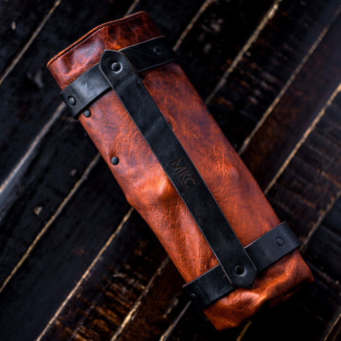 MKC Culinary Knife Roll made in the USA, featuring a rich brown leather exterior and black leather straps for secure closure.