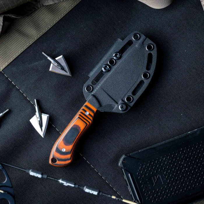 MKC Elk Knife in orange and black with a durable sheath, surrounded by hunting gear and accessories.