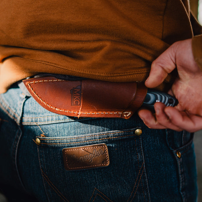 MKC Elk Knife leather sheath displayed on a belt, showcasing horizontal carry with a knife partially visible.