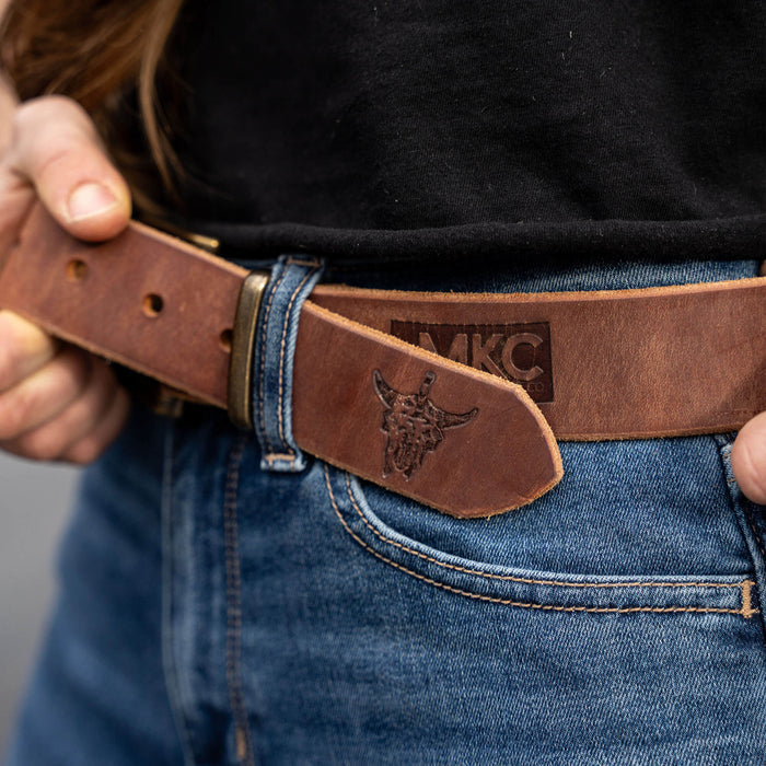 Brown MKC leather belt featuring a branded logo, worn with denim jeans, showcasing durability and style for everyday use.
