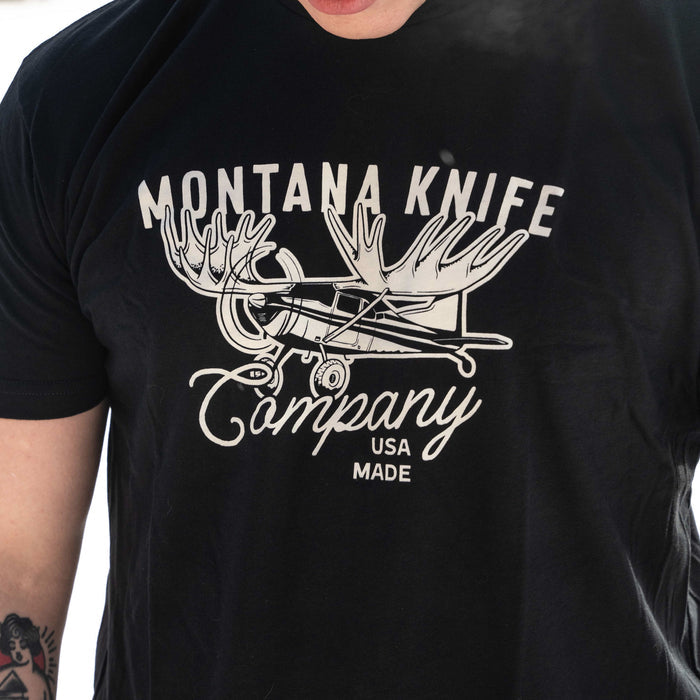 Black MKC Moose Tee featuring a graphic of a moose with airplane wings and the text Montana Knife Company USA Made.