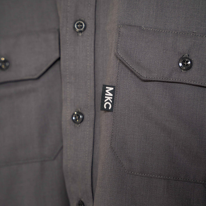 Graphite MKC shop shirt featuring button closures and dual chest pockets, made in the USA for durability and style.