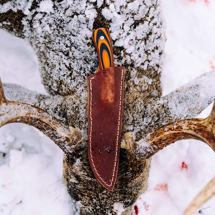 MKC Whitetail vertical leather sheath resting on a deer antler, showcasing its rugged design and craftsmanship.