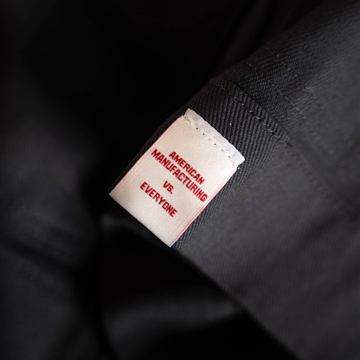 Charcoal MKC work jacket featuring a tag that reads "American Manufacturing vs Everyone." Durable and USA made.