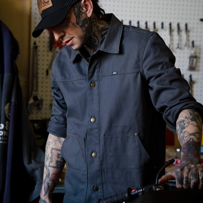 Charcoal MKC work jacket, USA made, featuring a classic design and practical pockets, worn by a tattooed individual.