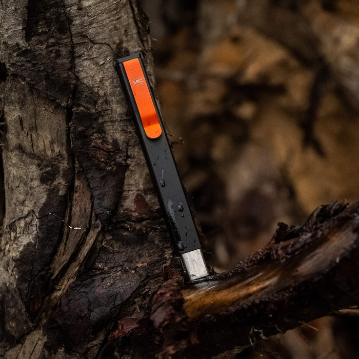 MKC X BIG IDEA DESIGN BIT BAR INLINE MAX, a sleek multitool with a black finish and orange accent, resting on textured wood.