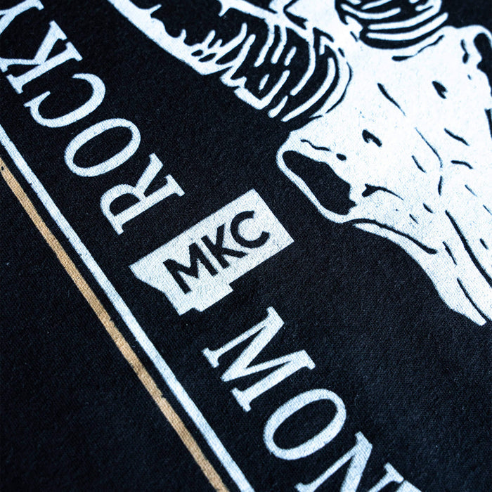 Black t-shirt featuring the MKC logo and Rocky Mountain Goat Alliance graphic, showcasing outdoor and hunting themes.