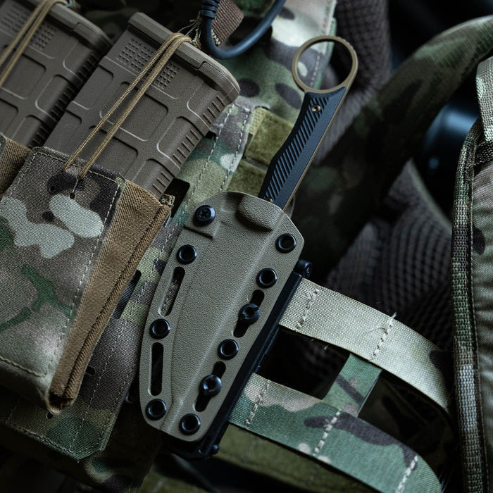 MOLLE-LOK attachment securing a knife sheath to tactical gear, featuring camouflage fabric and military-style pouches.