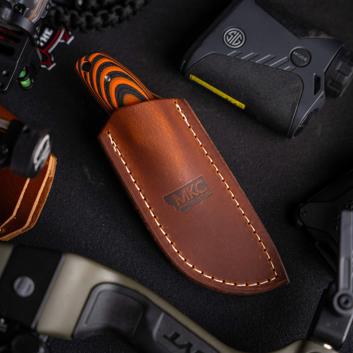 Vertical leather sheath for knives with MKC logo, featuring a durable design and contrasting stitching, ideal for belt carry.