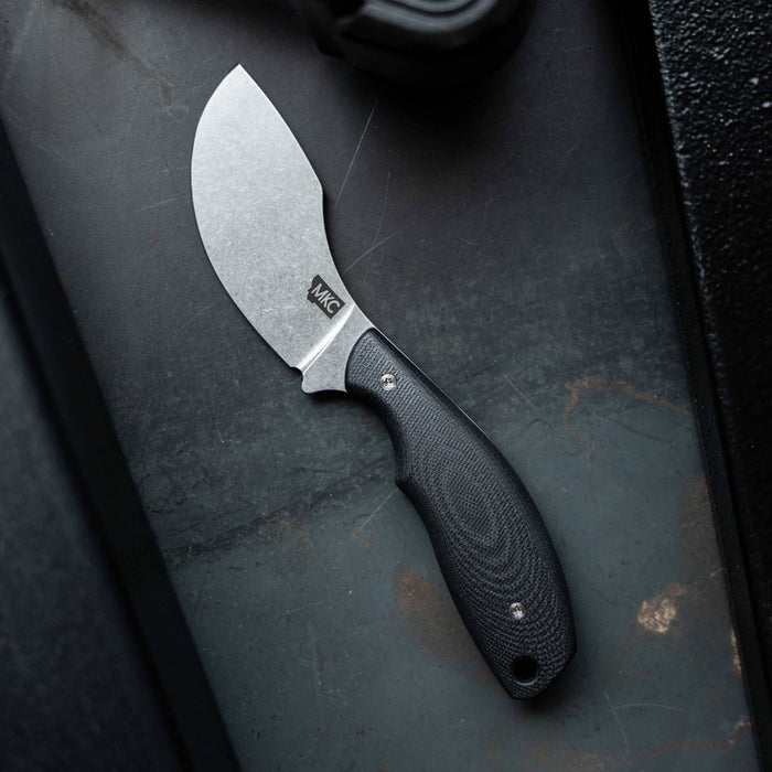 Montana Knife Company's PACKOUT SKINNER in black features a curved blade and ergonomic handle, ideal for hunting and outdoor tasks.