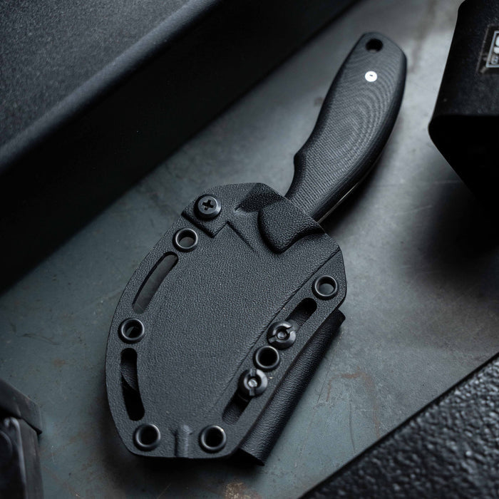 Black PACKOUT Skinner knife with a textured handle and sheath, designed for outdoor and hunting use.