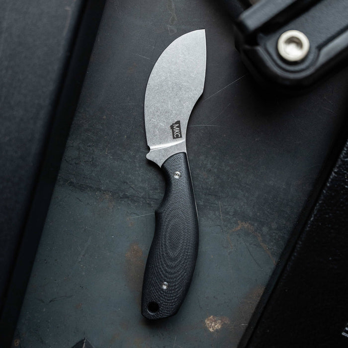 Montana Knife Company's PACKOUT SKINNER in black features a curved blade and ergonomic handle, ideal for outdoor use.