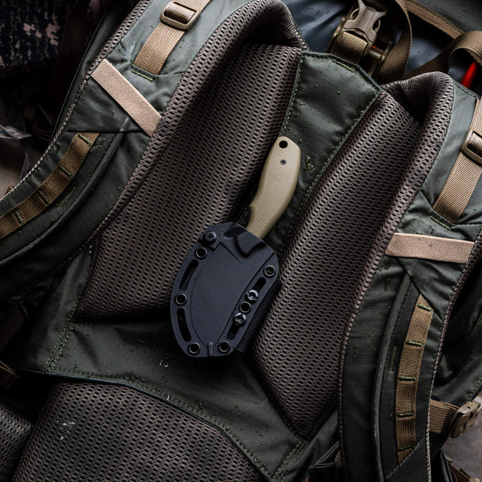 Olive PACKOUT SKINNER knife resting on a tactical backpack, showcasing its durable design and PVD finish.