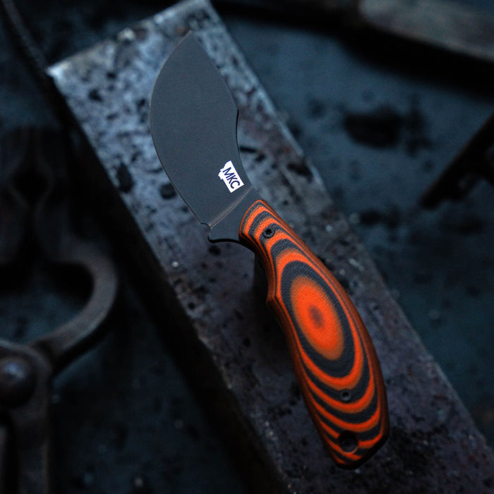 PACKOUT SKINNER knife with a black PVD blade and orange-black patterned handle, designed for outdoor and hunting use.