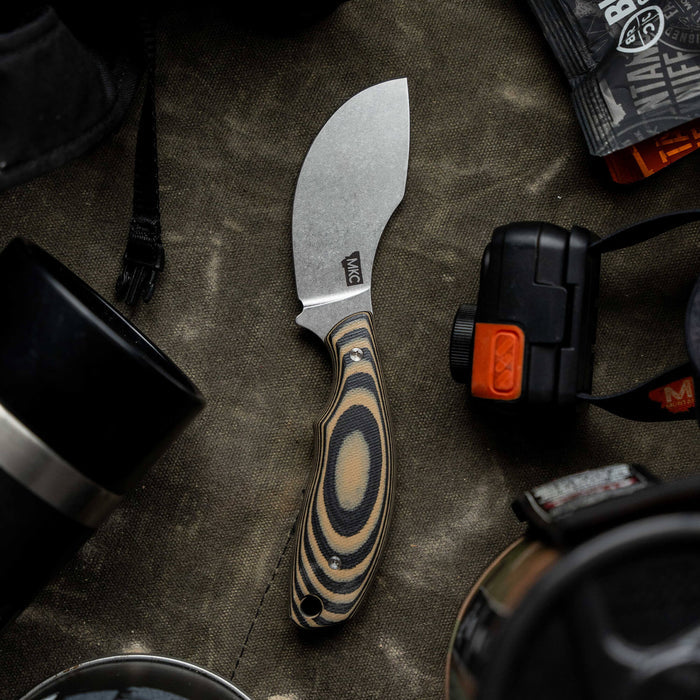 Montana Knife Company's PACKOUT SKINNER in tan and black, featuring a curved blade and ergonomic handle, ideal for outdoor use.