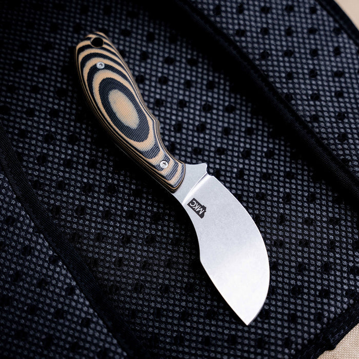 Montana Knife Company's PACKOUT SKINNER features a tan and black handle with a curved stainless steel blade, ideal for skinning.