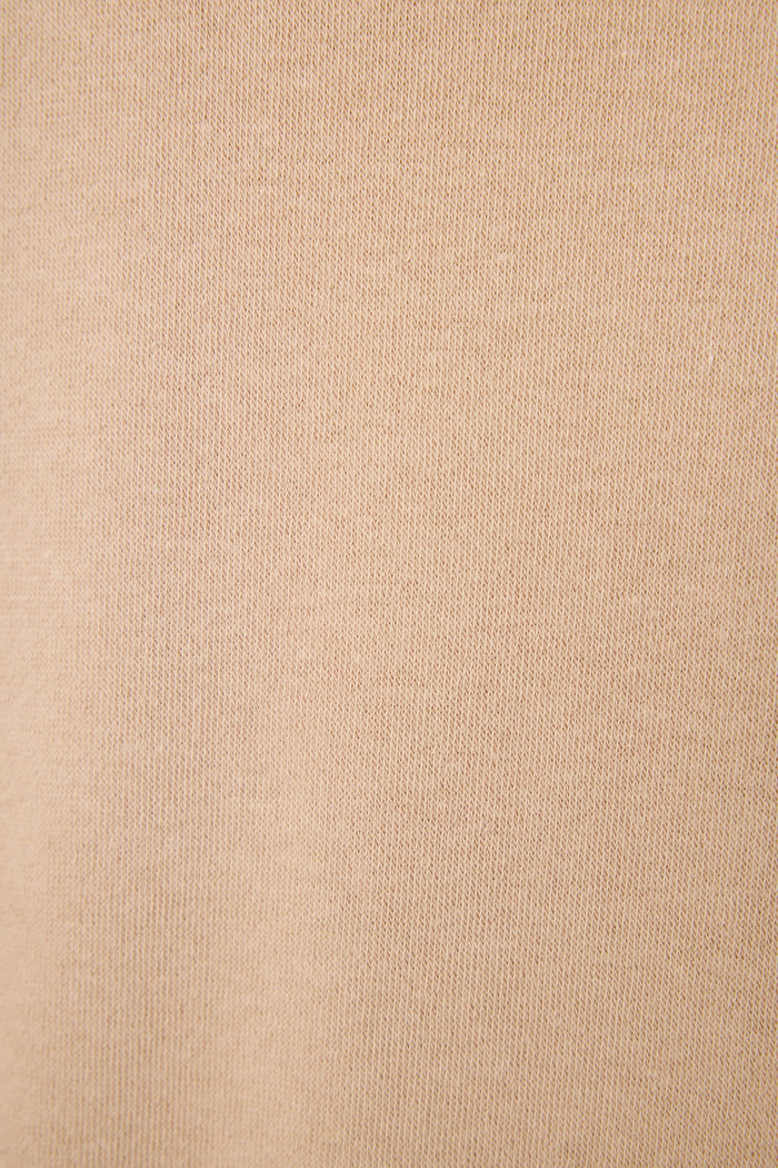Close-up of the Palms Away Warm Taupe fabric featuring soft beige fabric with a fine, slightly ribbed knit texture and subtle diagonal lines for a cozy lounge look.