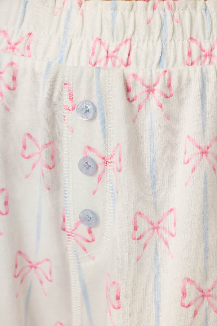 White cotton-modal jersey with light blue stripes, pink bow motif, and three light blue buttons; soft and cozy texture.