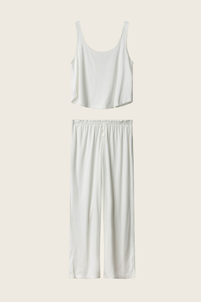The Pointelle Essentials Ivory PJ Set by P.J. Salvage features a sleeveless cropped tank and wide-leg, elastic-waist pants, both in white, displayed on a cream background.