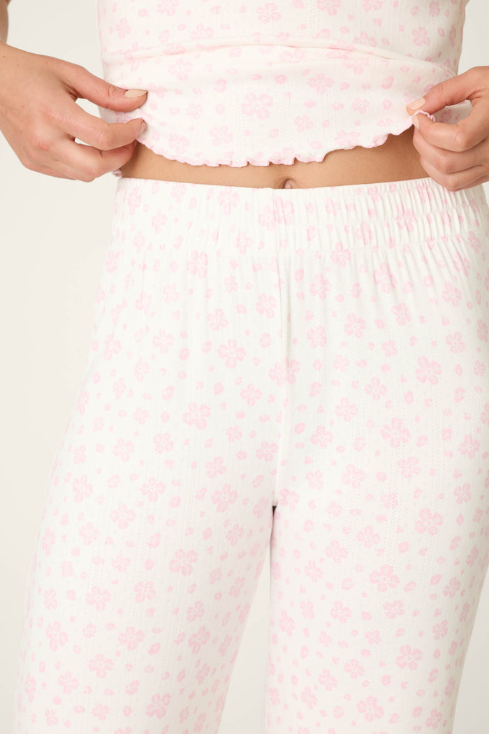 A person models the Pretty Petals Sweet Pink Floral Print Long PJ Set by P.J. Salvage, lifting the top to reveal their midriff. Only their torso and upper legs are shown.