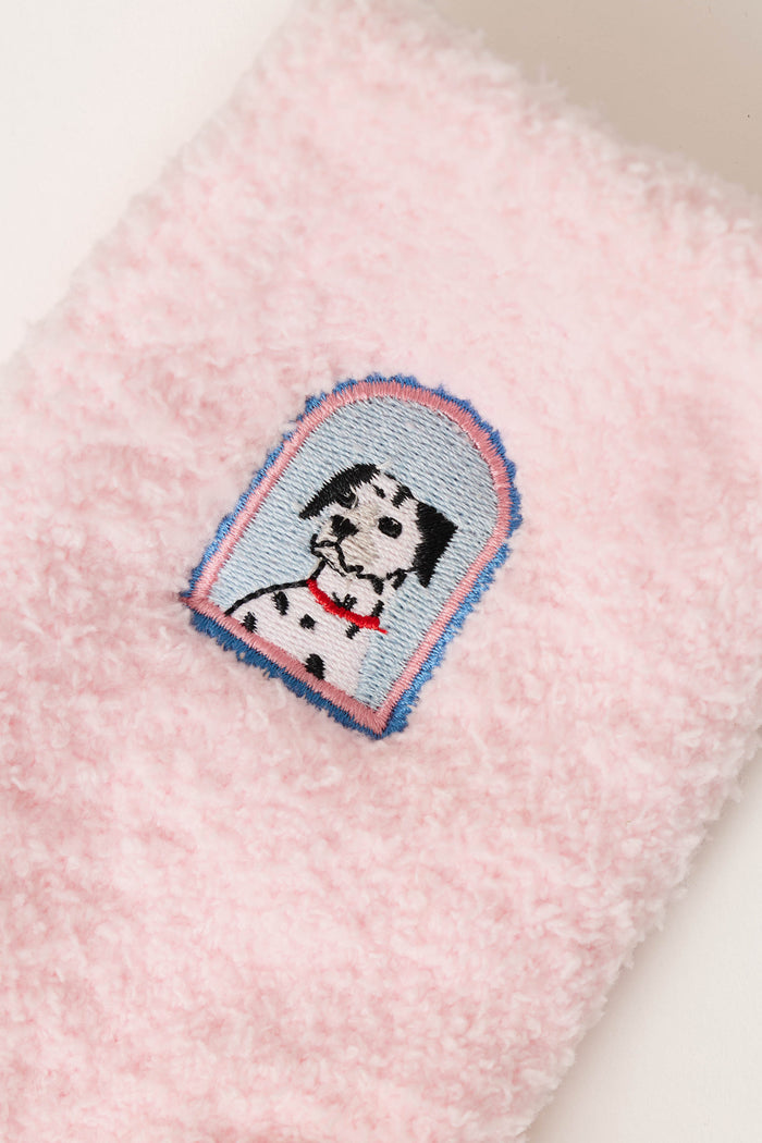 A pair of Puppy Portrait Socks by P.J. Salvage features a fluffy pink fabric adorned with an embroidered Dalmatian dog sporting a red collar, all framed by a blue and pink arched border.