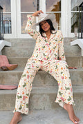 Wearing the Saddle Up Western Print Long Sleeve PJ Set by P.J. Salvage and a white hat, a woman sits barefoot on outdoor steps with pink cowboy boots beside her, posing casually in front of glass-paneled doors.