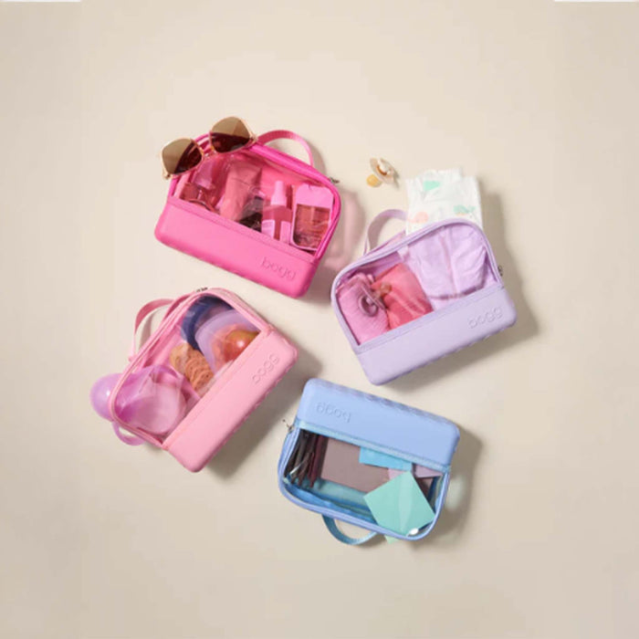 Bogg Clear Belt Bag in Pink Bubbles shown in four pastel colors filled with various baby and travel essentials, displayed flat on a beige background.