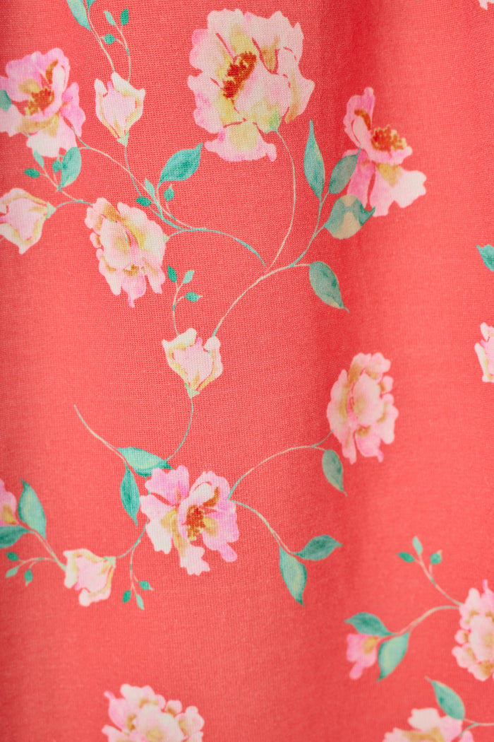 Close-up of the P.J. Salvage Siesta Dreams Dark Coral Floral Print Long PJ Set, featuring light pink flowers with green leaves on winding stems over a solid dark coral background.