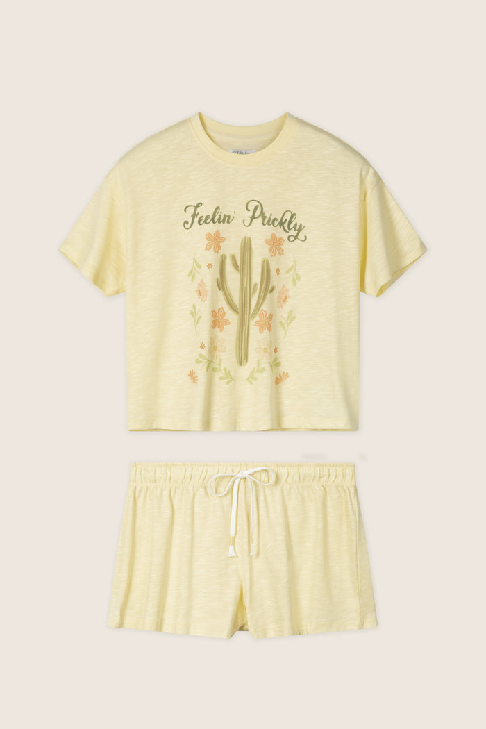The P.J. Salvage Softee "Feelin' Prickly" Graphic Print Short PJ Set features a light yellow relaxed fit with a cactus design crop top reading "Feelin' Prickly" and comfy shorts with an elastic waistband and drawstring.