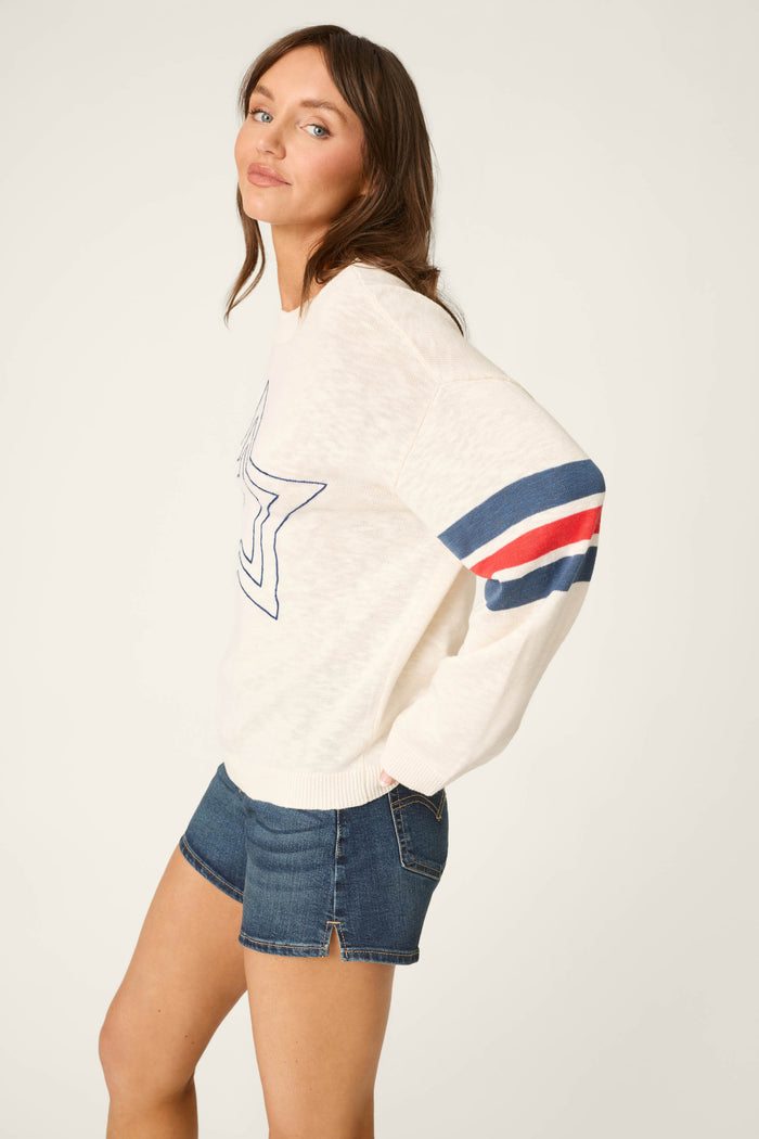 White fabric featuring a blue outlined star on the front and stripes in blue and red along the sleeves.