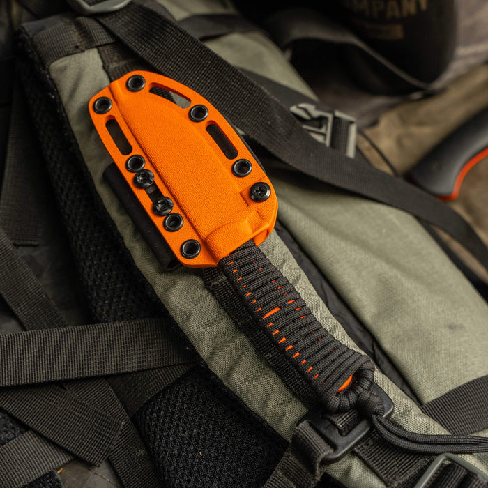 Bright orange Kydex sheath for the Stoned Goat 2.0 knife, attached to a rugged backpack, showcasing durability and functionality.