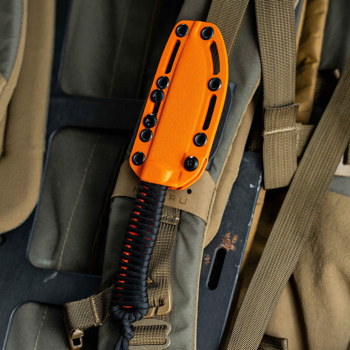 Bright orange Kydex sheath for the Stoned Goat 2.0 knife, secured to tactical gear with paracord and hardware.