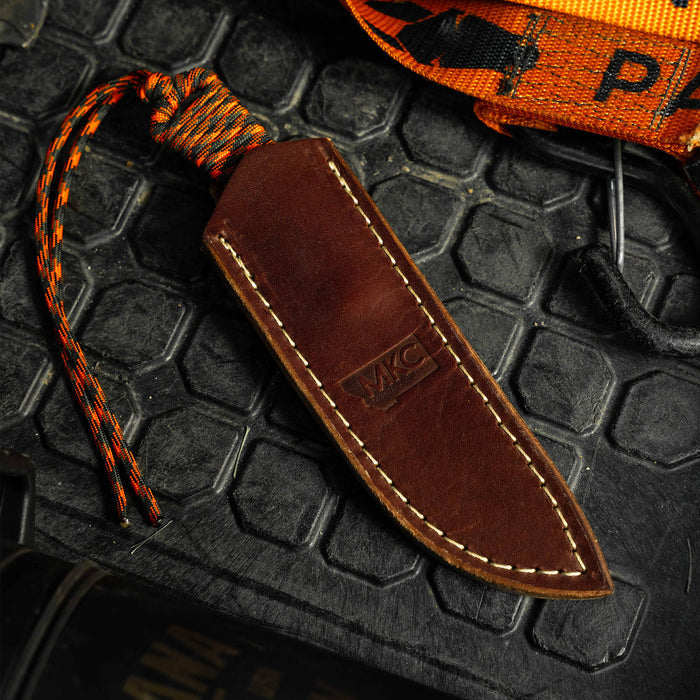 Stoned Goat 2.0 leather sheath for vertical belt carry, featuring a rich brown finish and orange paracord lanyard.