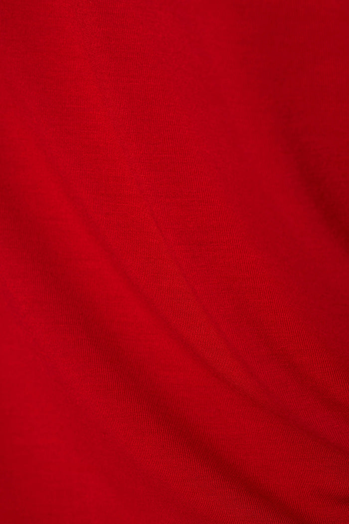 A close-up of bright red fabric with soft folds and a fine knit texture.