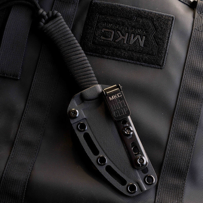 Tactical Speedgoat knife in black with a durable sheath and utility clip, resting on a tactical bag.