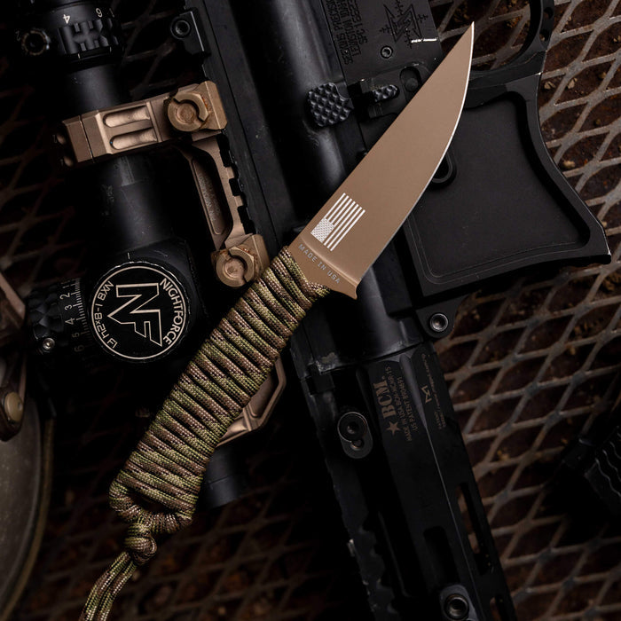 Tactical Speedgoat knife in Coy/Multicam with a paracord handle, positioned on tactical gear and accessories.