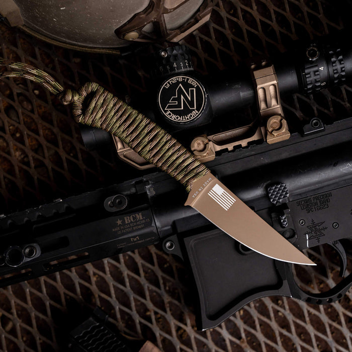 Tactical Speedgoat knife in Coy/Multicam, featuring a paracord handle, placed on a tactical rifle setup.