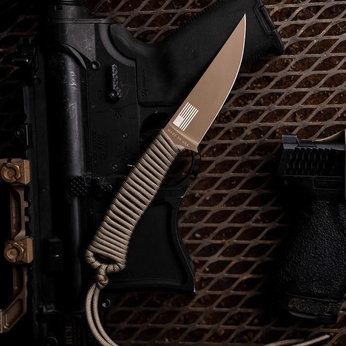 Tactical Speedgoat knife in coy/olv colorway, featuring a durable blade and paracord handle, displayed with tactical gear.