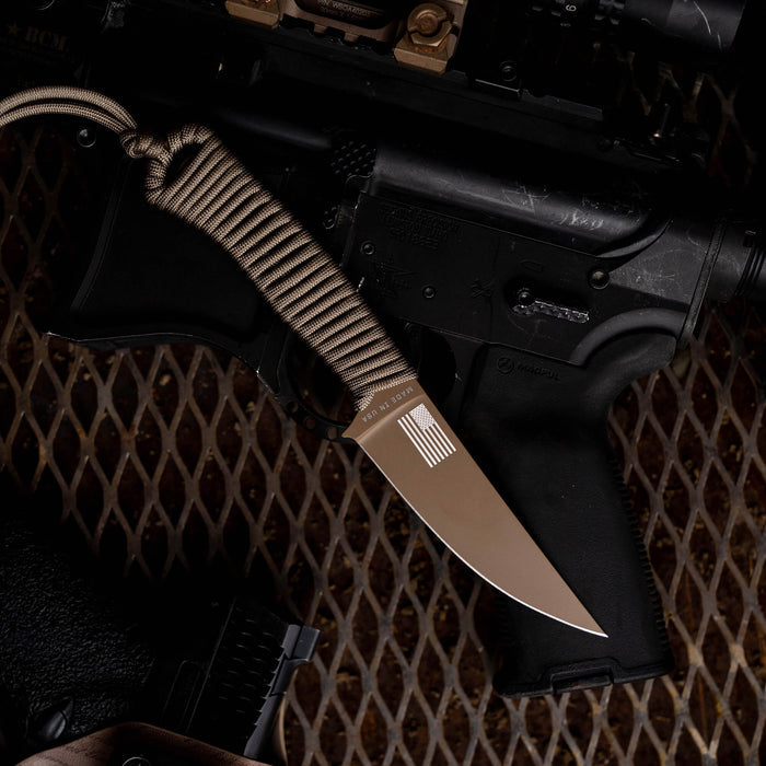 Tactical Speedgoat knife in coy/olv colorway, featuring a textured handle, displayed alongside tactical firearms.