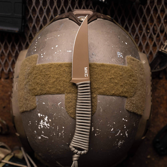 Tactical Speedgoat knife in coy/olv colorway resting on a tactical helmet, showcasing its sleek design and grip.