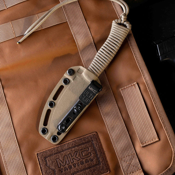 Tactical Speedgoat knife with a coy/olive drab sheath resting on a tactical bag, showcasing its durable design.