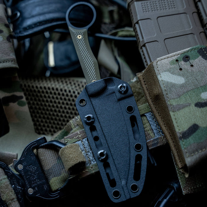 TEK-LOK belt attachment secured to tactical gear, showcasing a knife sheath and camouflage fabric background.