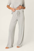 A person wearing P.J. Salvage Textured Essentials Heather Grey Open Leg Pants with a short-sleeve top. The ribbed knit loungewear set is loose-fitting; the person is barefoot and their face isn't visible.