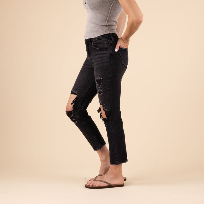 Side view of the black straight-leg jeans showing the relaxed fit through the leg and visible knee distressing on one side. The jeans maintain a clean line from hip to ankle.