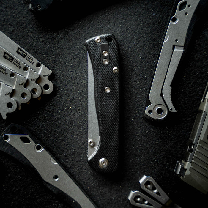 Montana Clip Deletion Kit featuring a sleek folding knife with a textured handle, surrounded by various knife components.