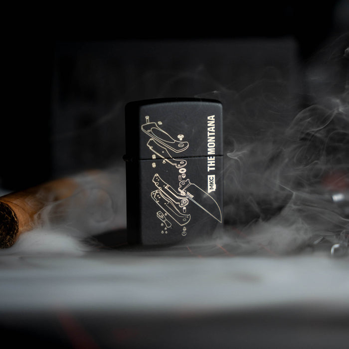Black Zippo lighter featuring Montana Knife Company design, surrounded by smoke and a cigar, showcasing American craftsmanship.