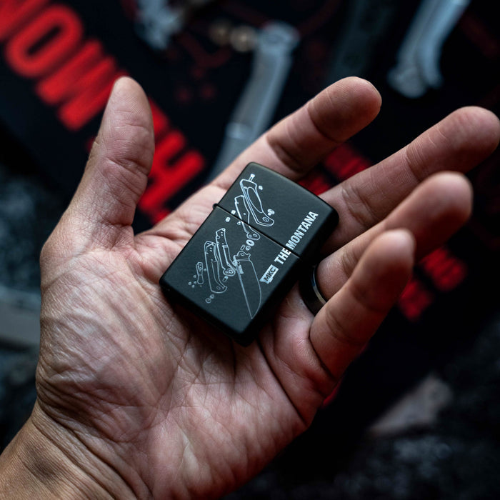 Montana Traditional windproof Zippo lighter held in a hand, featuring a sleek black design with intricate graphics.