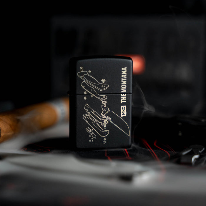 Montana Traditional windproof Zippo lighter featuring a detailed graphic design, set against a smoky background.