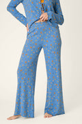 Model stands barefoot against a plain background, showcasing the P.J. Salvage Tiny Blooms Paris Blue Floral Print Pajama Pants; only the lower face and body are visible.